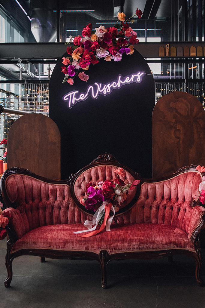 Velvet love seat with neon sign, pink florals for a wedding reception designed by Joy By Joelle.