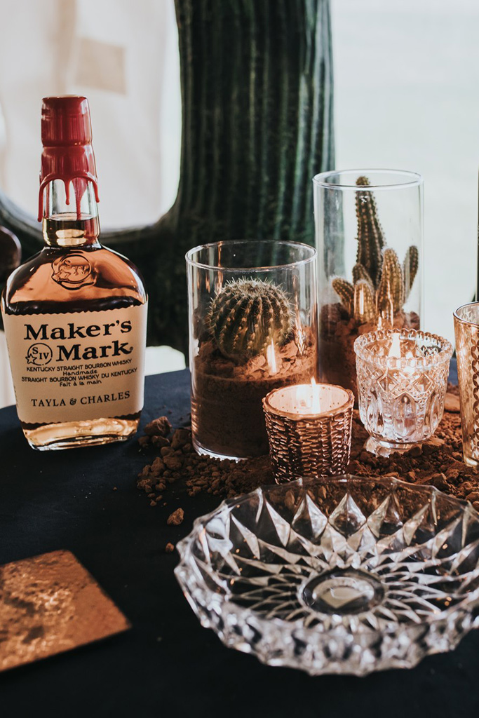 Rustic wedding reception with whiskey, cactus and candles for table decor designed by Joy By Joelle.